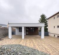 A family house in Nováčany with a paved courtyard and an adjacent wall.