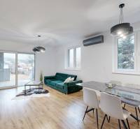 Living room in a family house with a wood-patterned floor, green sofa, and dining table.