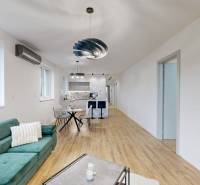 Living room with a kitchenette, sofa, and wooden decor flooring in a family house.