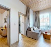 Interior of a holiday apartment with a sofa and wood-patterned flooring, delicate curtains.
