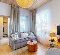 Living room in a holiday apartment with wood-patterned flooring and large curtains.