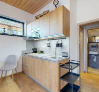 A kitchen in a holiday apartment with a wooden decor floor, entrance to the bathroom.