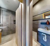 Bathroom in a holiday apartment with wooden decor and gray tiles, shower and sink.