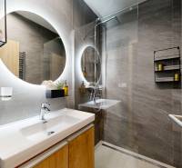 Bathroom in a holiday apartment with a sink, shower, round mirror, and decoration.