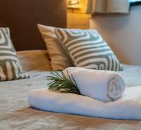 In the vacation apartment, towels and patterned pillows are placed on the bed.