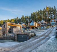 Wooden cottages in the resort on Do Doliny Street in Liptovský Mikuláš, surrounded by forest.