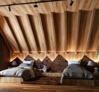 Attic bedroom with two beds, wooden decor, and a forest motif on the wall.