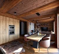 Interior of house construction with wood-patterned flooring, wooden beams, and a fireplace.