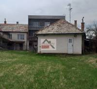 A family house in Studená with a large plot and older buildings in the background.