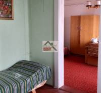 A room in a family house with carpets, older furniture, and a painted picture on the wall.