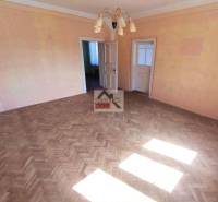 Living room with parquet flooring and a chandelier in a family house, two doors, light orange walls.