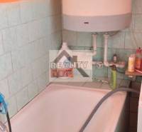 Bathroom with a bathtub, water heater, and tiles.