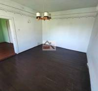 Interior of a family house with a dark wood-patterned floor and a chandelier.
