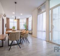 A dining room with large windows, comfortable chairs, a wooden table, interior on Hviezdoslavova Street.