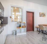 Kitchen and dining room in a 4-room apartment on Hviezdoslavova Street with light furniture and wooden flooring.