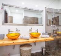 Bathroom on Hviezdoslavova Street with a wooden sink and glass bowls in a 4-room apartment.