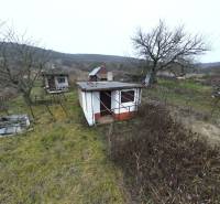 Cottages and trees in the vast vineyards in Nána with hills in the background.