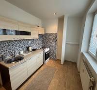 A kitchen in a 2-room apartment with a modern kitchen unit and a floor with a wooden decor.