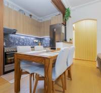 A kitchen in a 2-room apartment with a dining table, tiles, and a floor with a wooden decor.