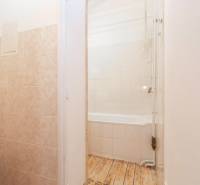 A bathroom in a 2-room apartment with a bathtub, toilet, and tiles in a decorative pattern.