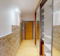 A hallway in the interior of a 2-room apartment with stone cladding and a floor with a wooden decor.