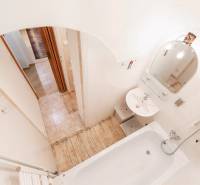 Bathroom in a 2-room apartment with a bathtub, sink, mirror, and tiles.