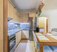 A kitchen in a 2-room apartment with a kitchen unit, a floor with a wooden decor, and a dining table.