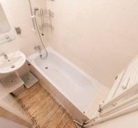 Bathroom in a 2-room apartment with a bathtub, sink, and white tiles.