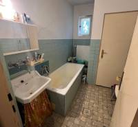 A bathroom in a family house with an old bathtub, sink, and tiles.