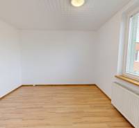 An empty room with a wooden floor, white walls, and a radiator in a 4-room apartment.