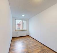 A narrow room with a wooden decor floor and a window in a 4-room apartment.