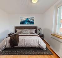 Bedroom with a bed, a picture on the wall, and a floor with a wooden decor in a 4-room apartment.