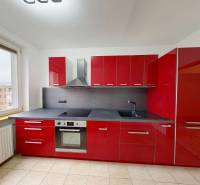 A kitchen in a 4-room apartment with red cabinets and a view from the window.