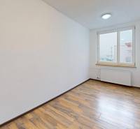 A bright room in a 4-room apartment with a wooden decor floor and a window.