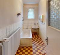Bathroom in a family house, tiled walls, bathtub, sink, radiator, checkered floor.