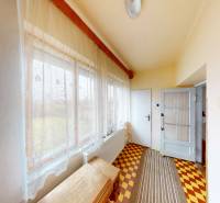 A hallway in a family house with curtains, tiles, and wooden paneling on the wall.