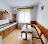 A kitchen in a family house with built-in cabinets and a corner bench, flooring with a wood decor.