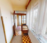 A narrow glazed space in a family house with a patterned floor and a table.