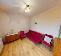 A room in a family house with a wooden decor floor and red seating.
