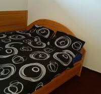 A double bed with a wooden headboard and black and white bedding in a holiday apartment.