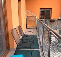 Balcony of a recreational apartment in Oščadnica with two metal chairs and glass doors.