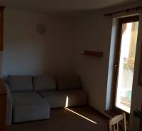 A room in a holiday apartment with a sofa, a cabinet, and balcony doors.