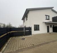 A family house in Plavecký Mikuláš with a paved courtyard and a black fence in the yard.