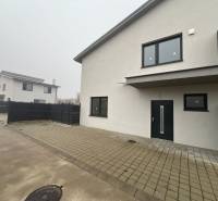 A family house in Plavecký Mikuláš with a paved courtyard and black fencing.