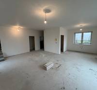 Spacious room in a family house with a concrete floor and a staircase.
