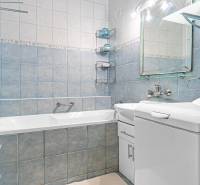 A bathroom with a built-in bathtub, sink, and blue wall tiles in a 4-room apartment.