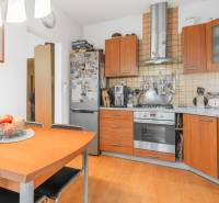 A kitchen in a 4-room apartment with a wooden decor floor and wooden cabinets.