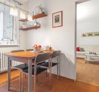 Dining area with a wooden table, shelves, and a view of the living room in a 4-room apartment.