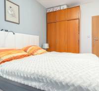 Bedroom in a 4-room apartment with a wooden wardrobe, a white headboard, and a picture on the wall.
