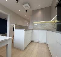 A kitchen in a 3-room apartment with a wooden decor floor and modern lighting.
